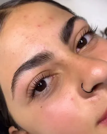Olho de perto com os cílios curvados pelo lash lifting e a sobrancelha penteada